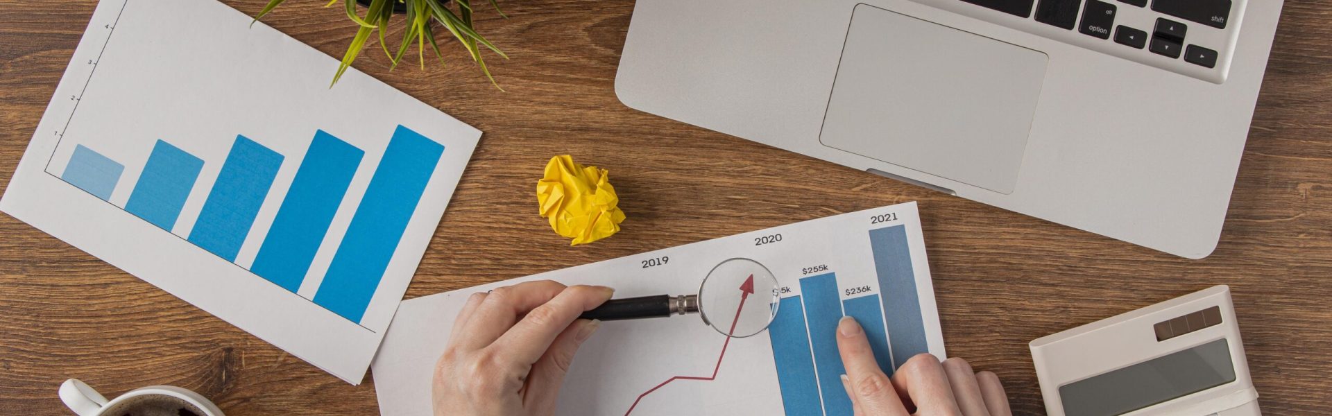 top-view-office-desk-with-laptop-growth-chart-analyzed-by-hands